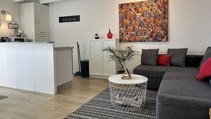 Ein modernes Wohnzimmer mit grauem Sofa, einem Couchtisch und einem farbenfrohen, abstrakten Gemälde an der Wand.