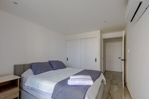 A bedroom with a bed, a bedside table, a wardrobe, and an air conditioning unit. - 200 Mts away from  the Caribbean Sea (Cartagena de Indias)