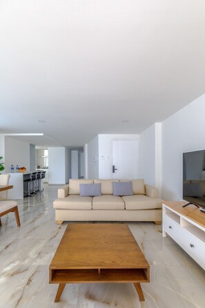 A modern living room with a sofa, coffee table, TV stand, and a kitchen area in the background. - 200 Mts away from  the Caribbean Sea (Cartagena de Indias)