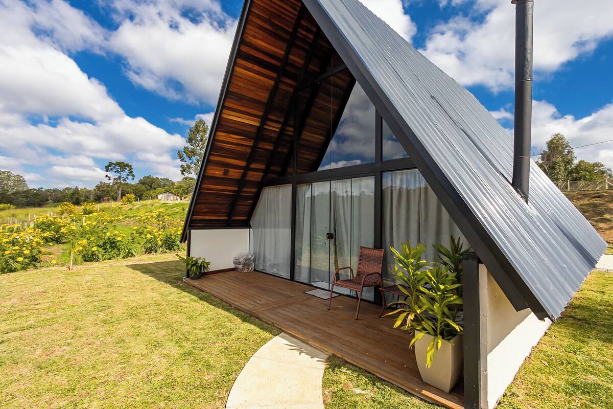 A modern house with a sloped roof, large windows, and a wooden deck.