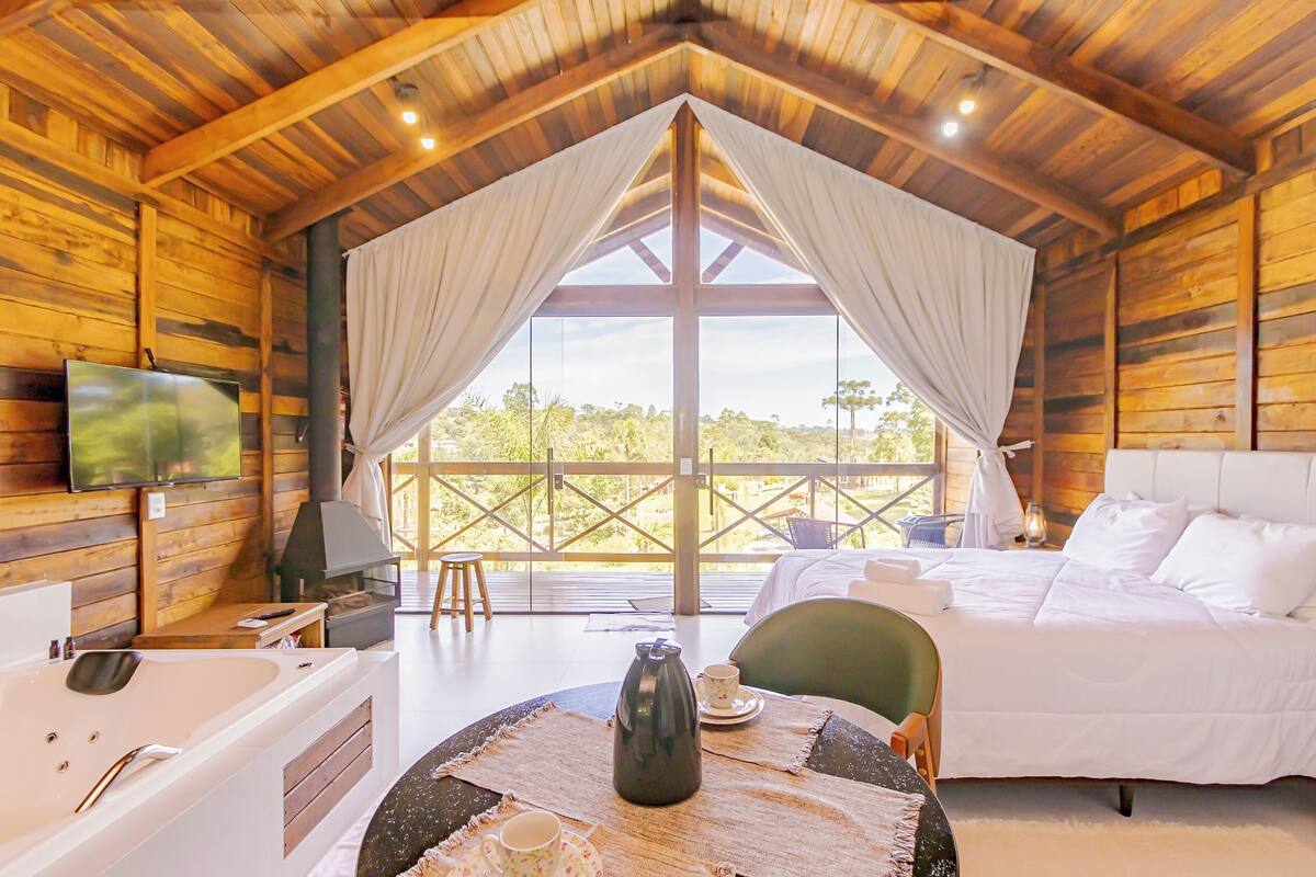 A cozy cabin with a large bed, a sitting area with a table, and a TV mounted on the wall.