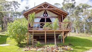 A wooden cabin with a balcony, surrounded by a garden with various plants and flowers. - VILLA ESTORIL (Campina Grande Do Sul)