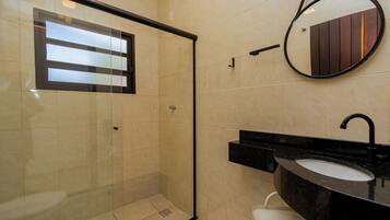 A modern bathroom with a glass-enclosed shower, a black sink, and a mirror with a wooden panel design.