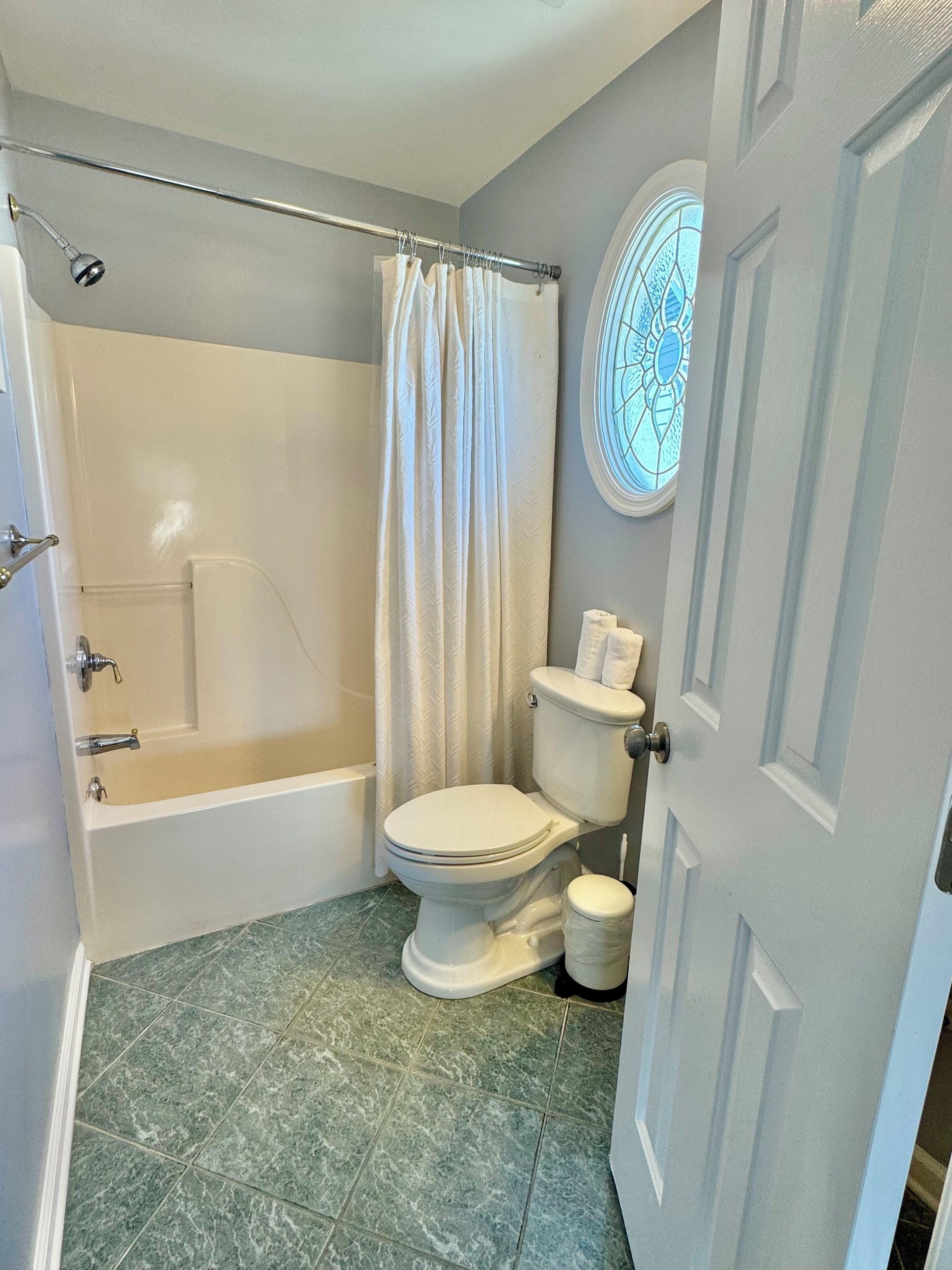 A bathroom with a bathtub, toilet, and shower curtain.