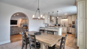 Una cocina amplia con una mesa de comedor de madera, armarios blancos y una pared decorativa de piedra.