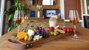 Un interior de madera con una mesa de madera que exhibe una tabla de embutidos, dos copas de vino y un espejo en la pared.