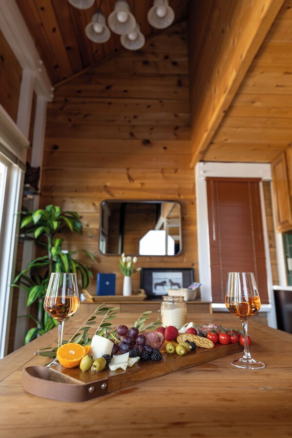 Ein Holzinterieur mit einem Holztisch, auf dem eine Wurstplatte, zwei Weingläser und ein Spiegel an der Wand zu sehen sind.