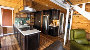 Una cocina moderna con muebles oscuros, electrodomésticos de acero inoxidable y techo de madera.