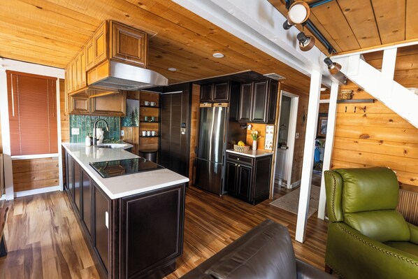 A modern kitchen with dark cabinetry, stainless steel appliances, and a wooden ceiling. - Sunriver Charmer-Updated Family Cabin w/SHARC, Village Access-Comfortable for 6 (Sunriver)
