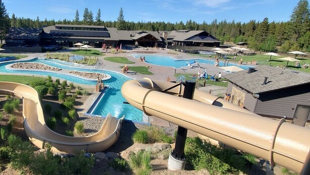 Un resort con varias piscinas, un tobogán acuático y un edificio grande de diseño rústico.