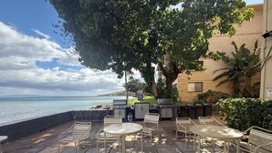 An outdoor patio with stone flooring, metal chairs, a table, and a grill. - Cool 1BD Entire Condo On The Beach in Maalaea Harbor (Wailuku)