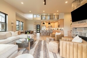 A spacious living area with a sofa, armchairs, a coffee table, and a fireplace. - New and Fun in Deer Valley East Village - Free Mountain Mover on demand ski shuttle (Heber City)