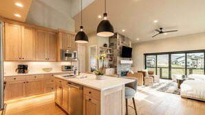 A modern kitchen with wooden cabinets, a central island, and pendant lighting. - New and Fun in Deer Valley East Village - Free Mountain Mover on demand ski shuttle (Heber City)