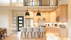 A modern kitchen with bar stools, a dining area with a table and chairs, and a loft space with a balcony. - New and Fun in Deer Valley East Village - Free Mountain Mover on demand ski shuttle (Heber City)