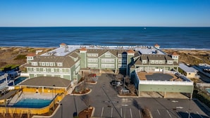 Hotel a la costa amb diversos edificis, un aparcament i una piscina.