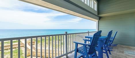 A covered outdoor area with a view of the beach and ocean.
