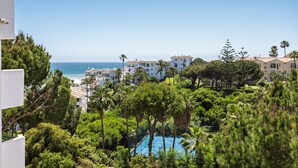Une vue sur la côte, avec un court de tennis entouré d’une végétation luxuriante et des bâtiments à l’architecture méditerranéenne.