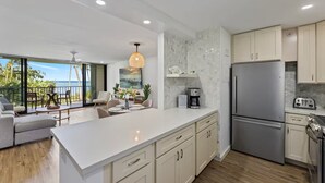 A modern kitchen with a large island, stainless steel appliances, and a view to the outdoors. - Valle Isle (Lahaina)