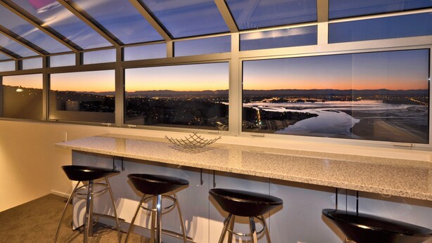 Eine moderne Küche mit einem großen Fenster, das auf eine städtische Silhouette im Abenddämmerung blickt.