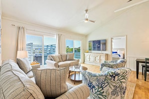 Relax in a spacious living area with a large sofa set, coffee table, and dining table, offering stunning views of the surrounding area.