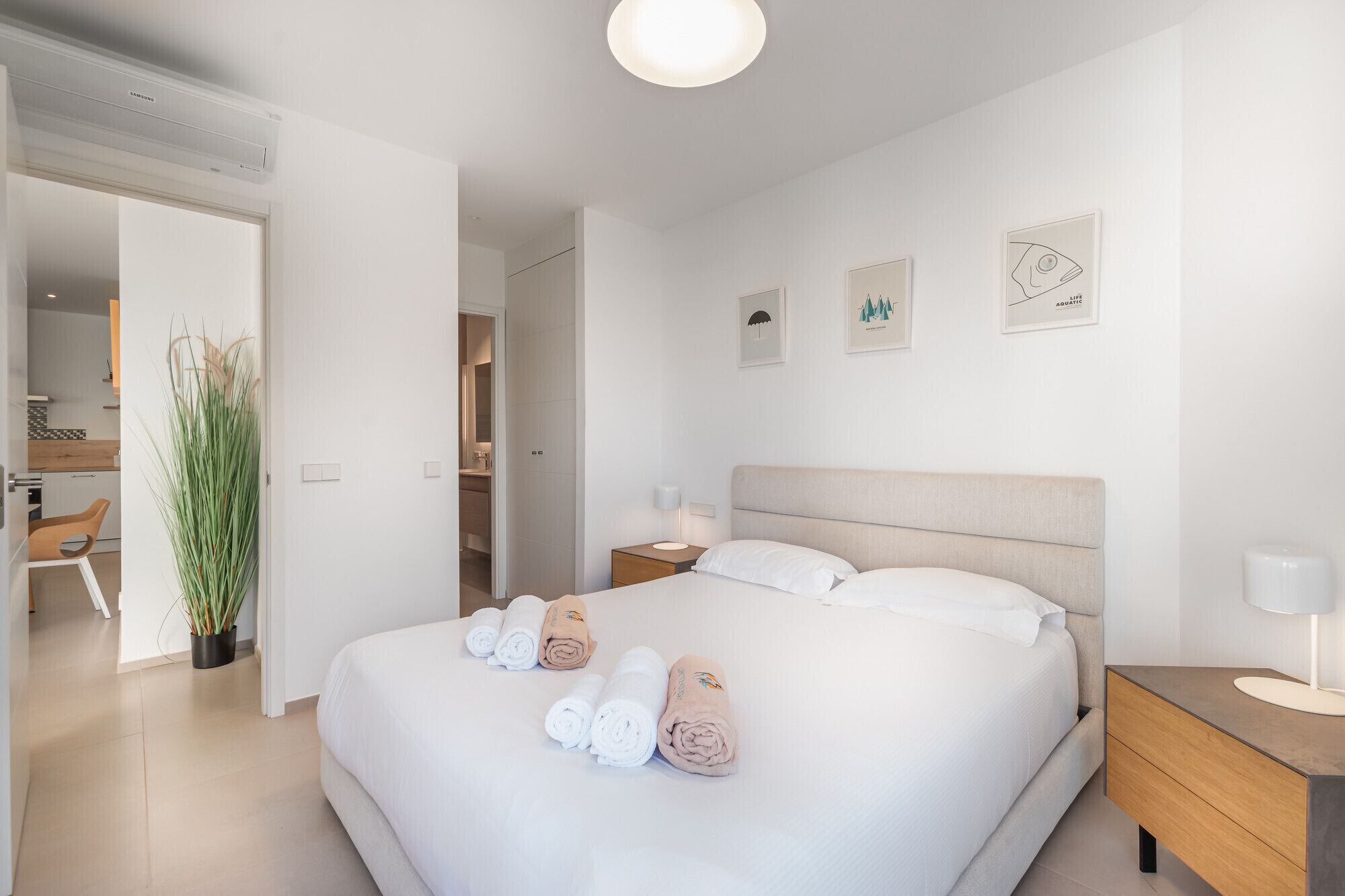 Une chambre d’hôtel moderne avec un grand lit, une table de chevet avec une lampe et une vue sur la salle de bain.