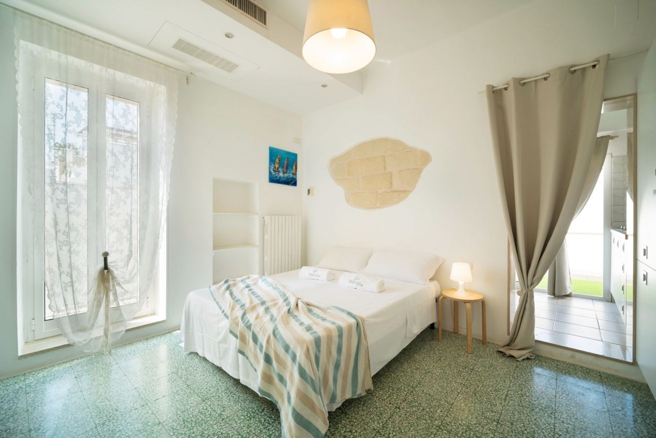 Hotelkamer met een bed, nachtkastje met lamp, raam met gordijnen en een wanddecoratie.