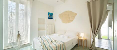 Hotelkamer met een bed, nachtkastje met lamp, raam met gordijnen en een wanddecoratie.
