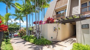 A modern building with a sloped roof, a covered walkway, and a sign indicating unit numbers. - Charming 1-bedroom condo in lovely Kihei with WiFi, AC (Kihei)