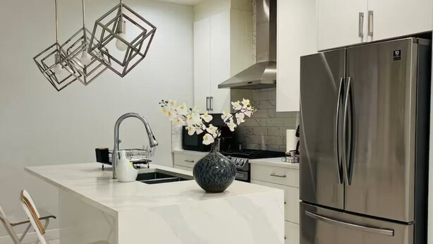 A modern kitchen with a large island, stainless steel appliances, and pendant lighting. - Luxury 3 Bedroom Home | Fireplace | 84” Pool Table| Air Conditioning| Garage (Edmonton)