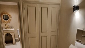 A bedroom with a large bed, a wardrobe, and a bathroom visible through an open door.