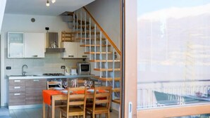 A modern kitchen with a wooden staircase, a dining area with a table set for two, and a large window overlooking a cityscape. - Elegant two-bedroom apartment with air conditioning and a large balcony overlooking the lake. Guests can relax in the shared swimming pool, immersed in a peaceful atmosphere. Perfect for a comfortable and unforgettable stay.The apartment is located on th (Bellano)