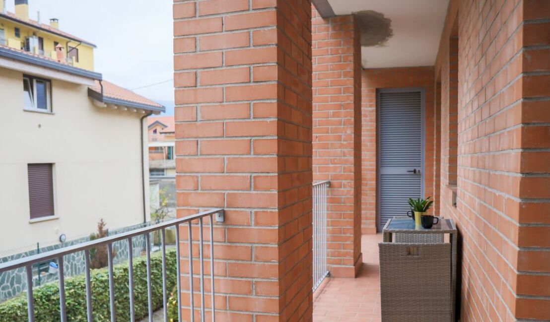 Un balcon avec une balustrade en métal, un pot de fleurs et une petite table.