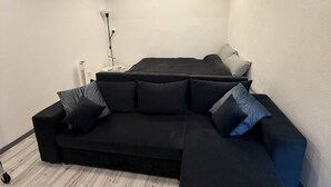 Ett modernt vardagsrum med en hörnsoffa, ett litet sidobord och en golvlampa.