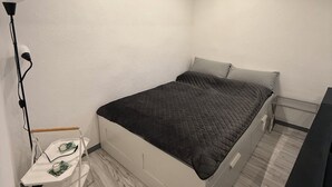 Ett modernt sovrum med en säng, sängbord, en lampa och en värmare.