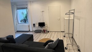 Ett modernt vardagsrum med en soffa, en tv och ett skåp med genomskinliga glasdörrar.