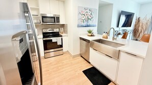 A modern kitchen with white cabinets, stainless steel appliances, and a black rug.