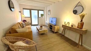 A living room with a sofa, a coffee table, a TV, and a console table with decorative items.