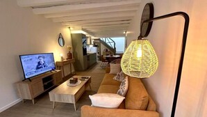 A living room with a television, sofa, coffee table, and a hanging lamp.
