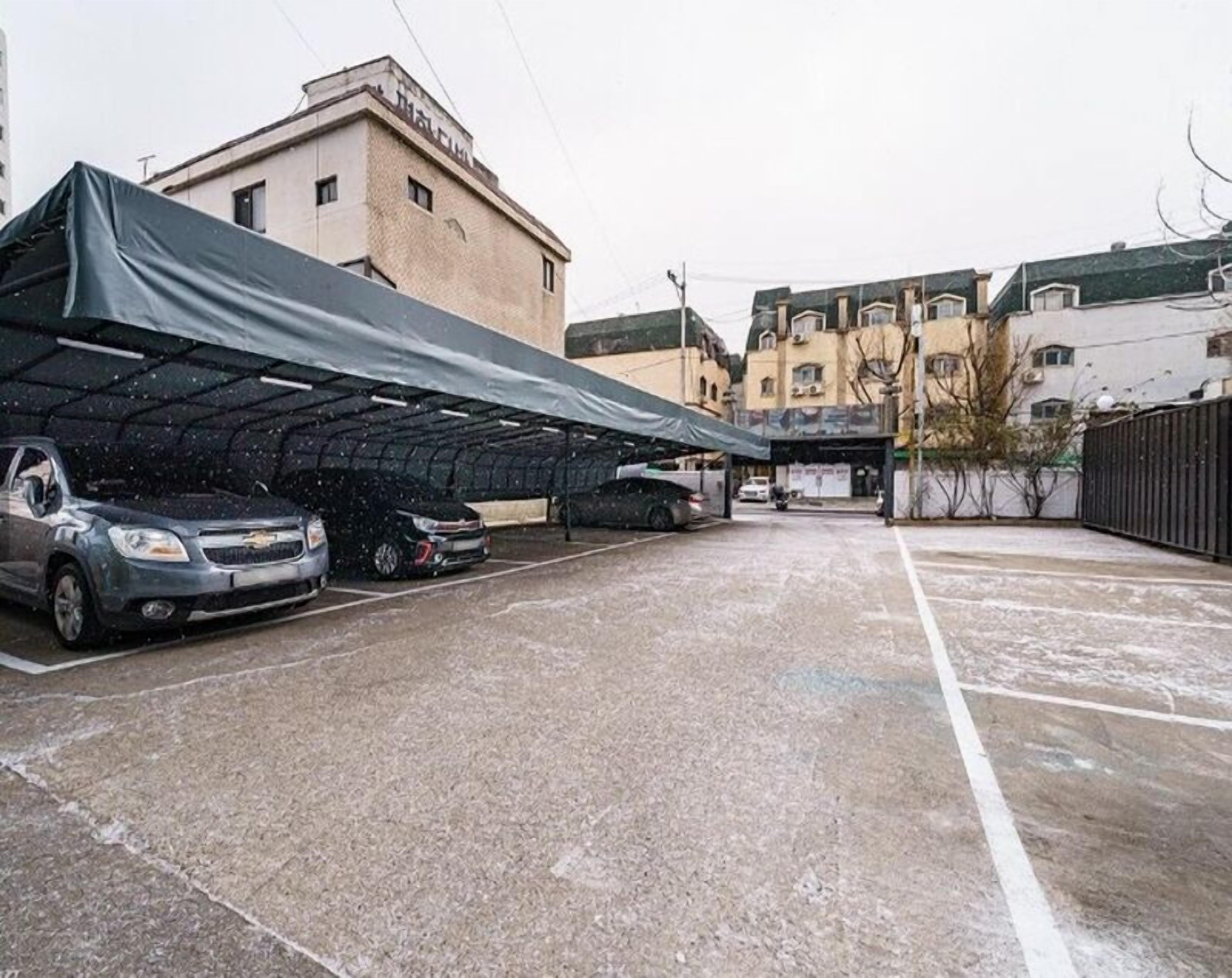 A covered parking area with several cars parked under a shelter.