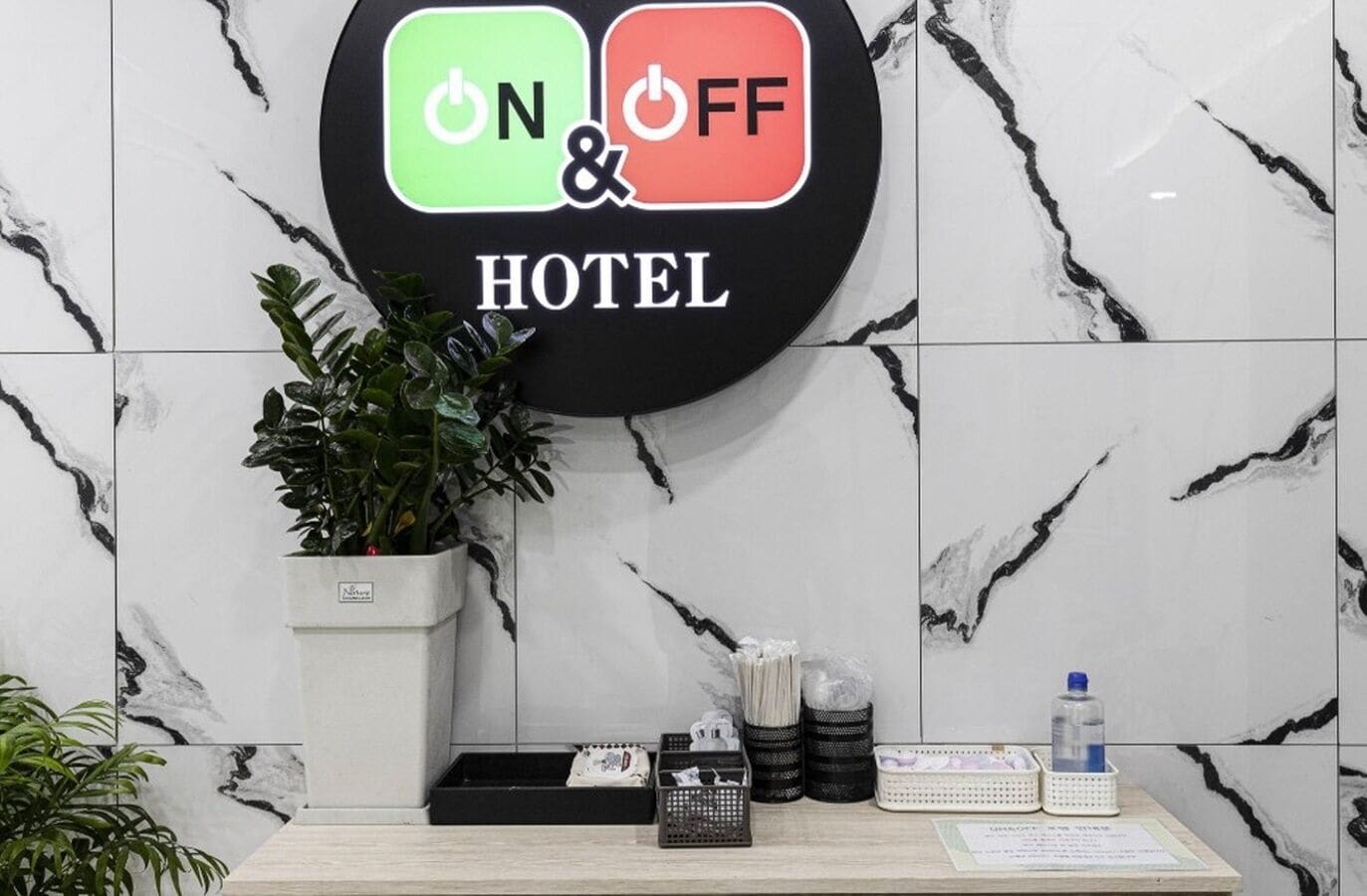 Una reception hotel con un cartello che indica lo stato dell'alimentazione, una pianta in vaso e diversi oggetti sul bancone.