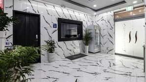 A modern lobby with marble flooring, a reception desk, a refrigerator, and a door labeled "Lounge". - ON and OFF-Sungui Station (Incheon)