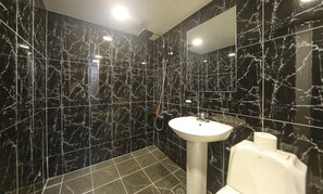 A bathroom with black marble walls and a white sink.