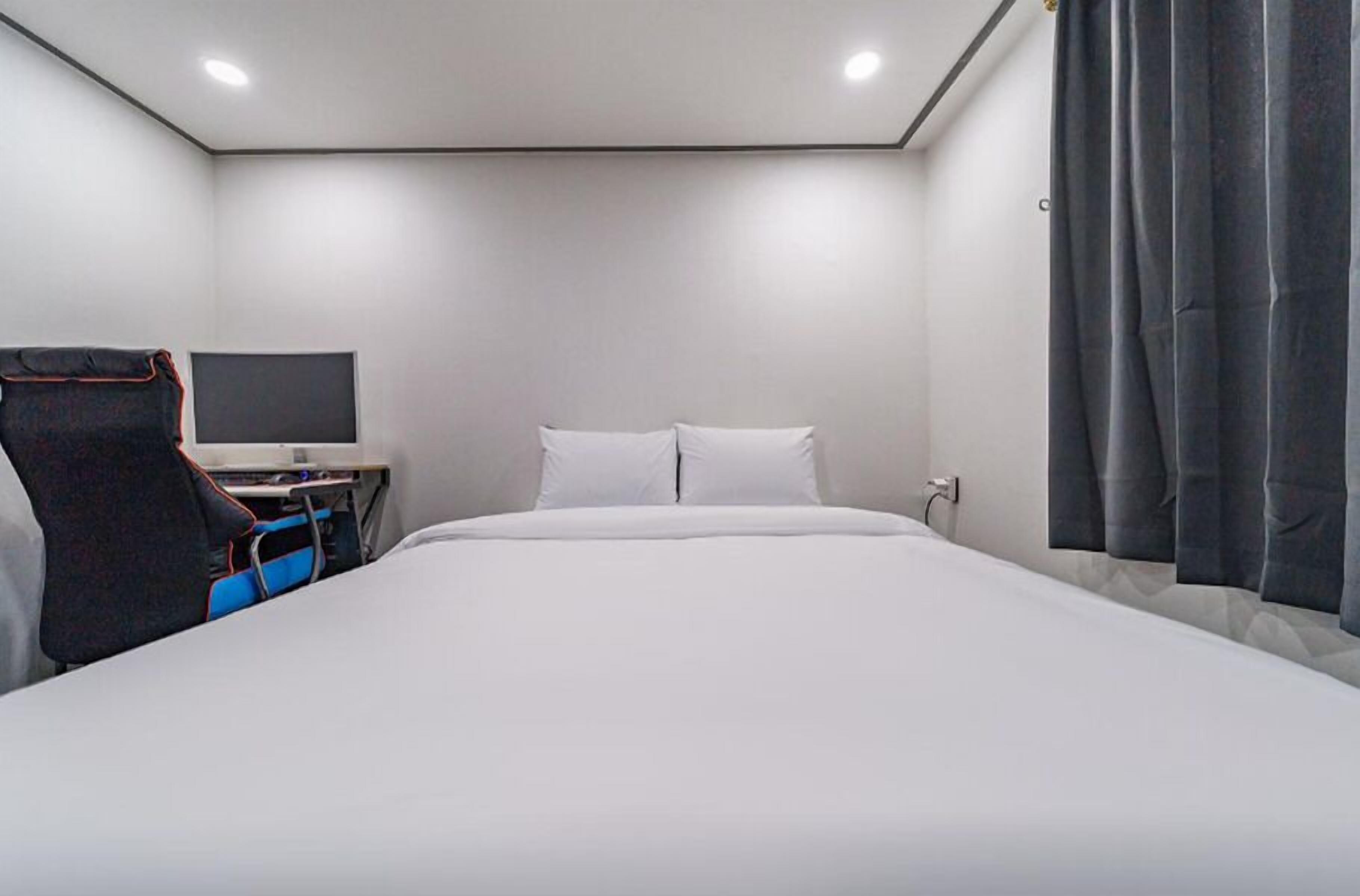 Ein modernes Hotelzimmer mit einem großen Bett, einem Schreibtisch mit einem Flachbildfernseher und einem Sessel.