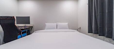 Ein modernes Hotelzimmer mit einem großen Bett, einem Schreibtisch mit einem Flachbildfernseher und einem Sessel.