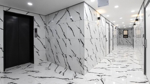 A hallway with marble walls and floors, a black elevator, and recessed ceiling lights. - ON and OFF-Sungui Station (Incheon)