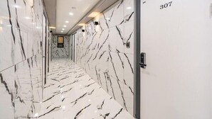 A hallway with marble flooring and walls, a door labeled '307', and recessed ceiling lights. - ON and OFF-Sungui Station (Incheon)