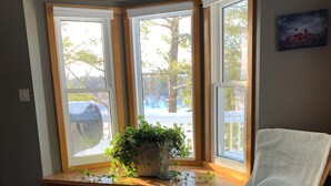 Ein Zimmer mit Erkerfenster, Holzakzente, einem Schaukelstuhl und einem gemusterten Teppich.