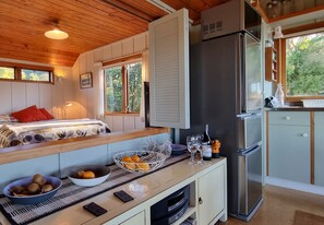 Eine kleine Küche mit Kühlschrank, Mikrowelle und einem Essbereich mit Tisch und Stühlen.