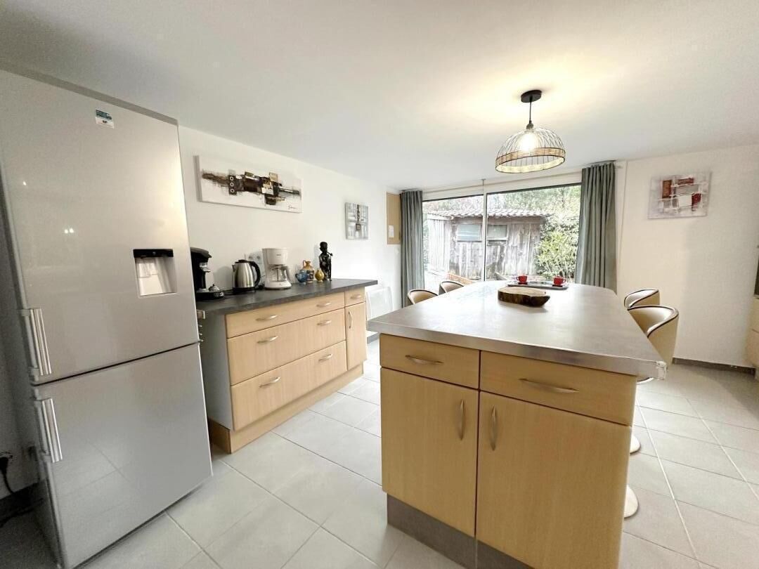 A modern kitchen with a refrigerator, stove, and dining area.