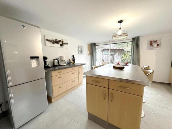 A modern kitchen with a refrigerator, stove, and dining area.
